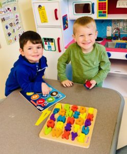 Two preschool boys play with letter blocks at EDS.